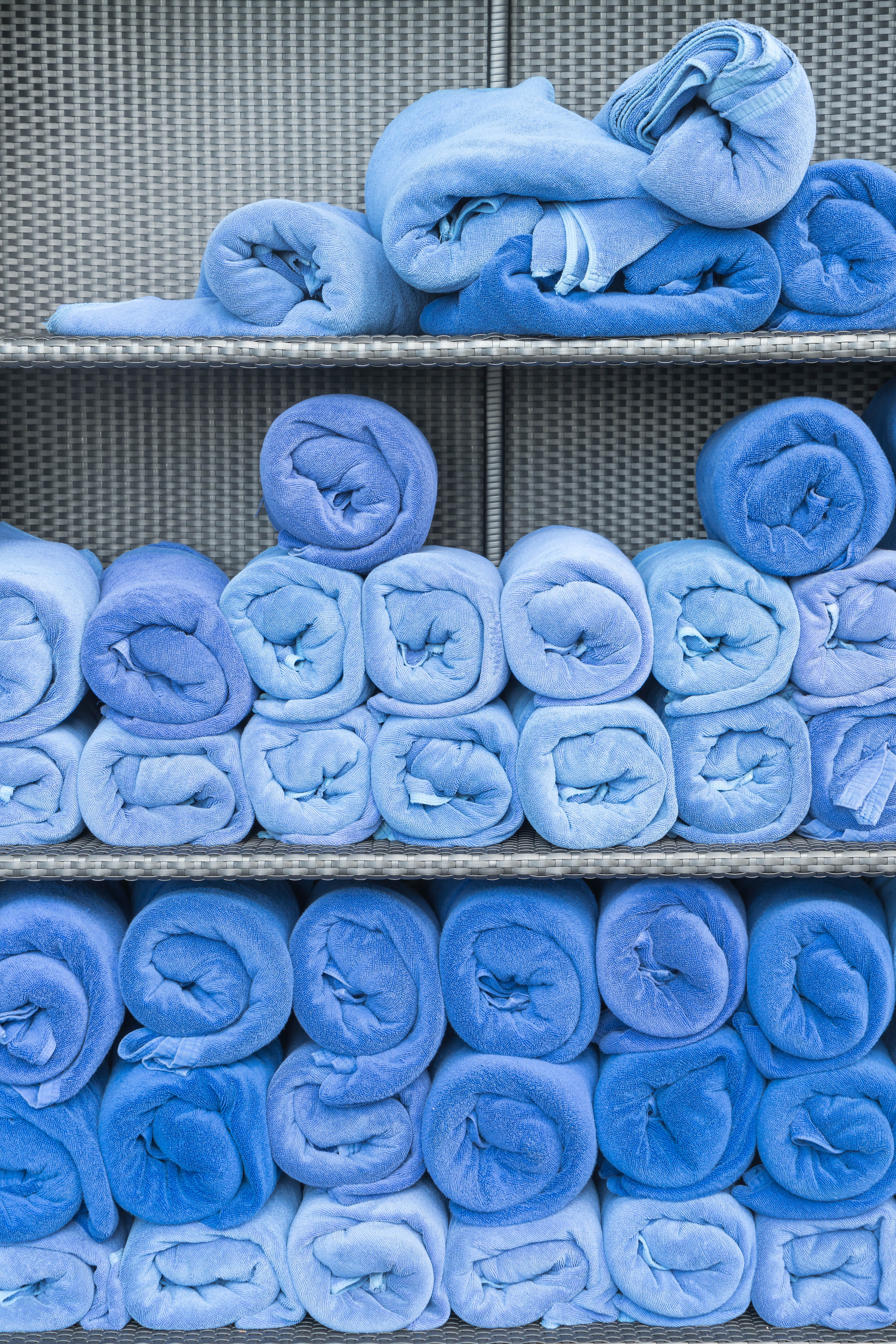 This photo shows a cupboard filled with rolled up towels